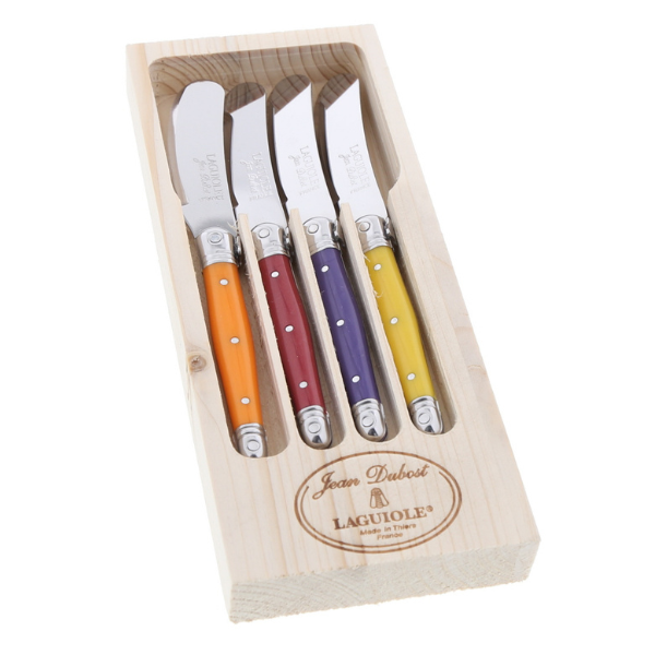 Individual colored-handle cheese spreader knife shown alongside soft brie on a wooden board